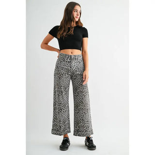 Woman wearing black crop top and leopard print wide-leg pants on a white background