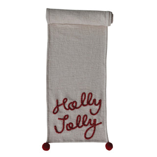 Styled view of cotton slub table runner with red Holly Jolly embroidery and pom-pom corners