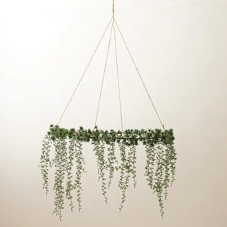 Frosted faux cedar hanging wreath with trailing greenery on iron frame