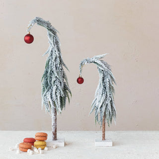 Styled view of snowy evergreen tree with red ornament