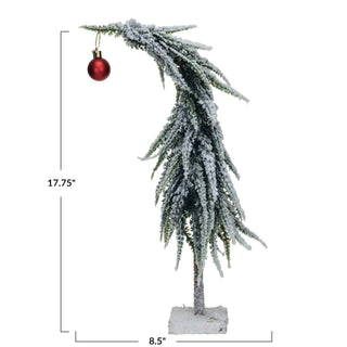 Detail view of red ball ornament on snowy faux evergreen tree