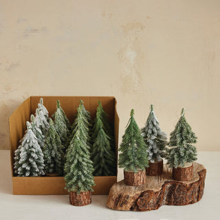 Snowy faux evergreen trees shown in four styles on wood slice bases