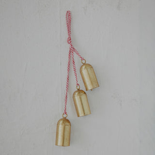 Close-up of weathered gold iron bells on red and white cord