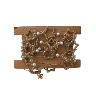 Styled view of gold star garland draped across a holiday mantel