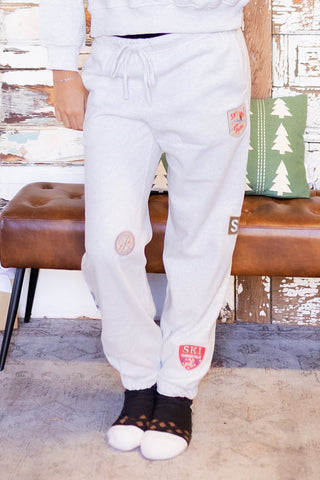 Heather oat fleece high-waist joggers with vintage ski resort patches and drawstring waist